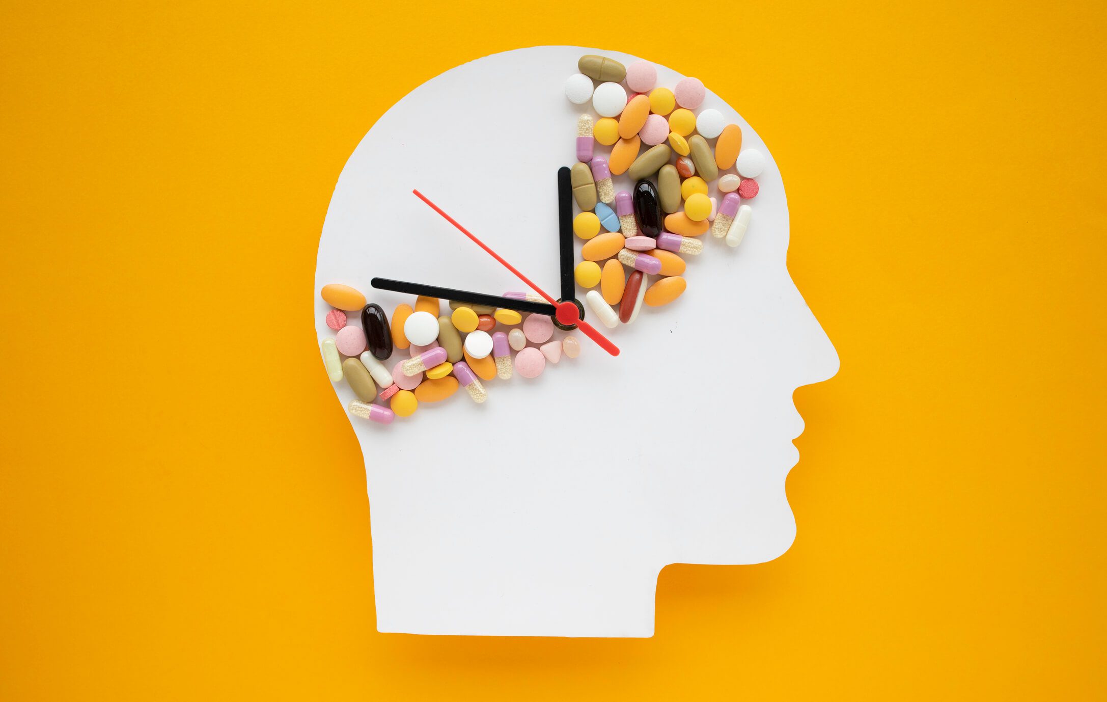 Head silhouette with pills and clock hands