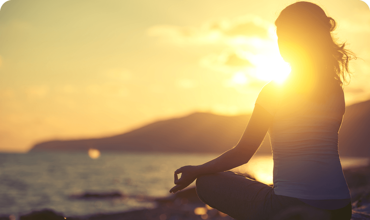 Silhouette of person meditating at sunset